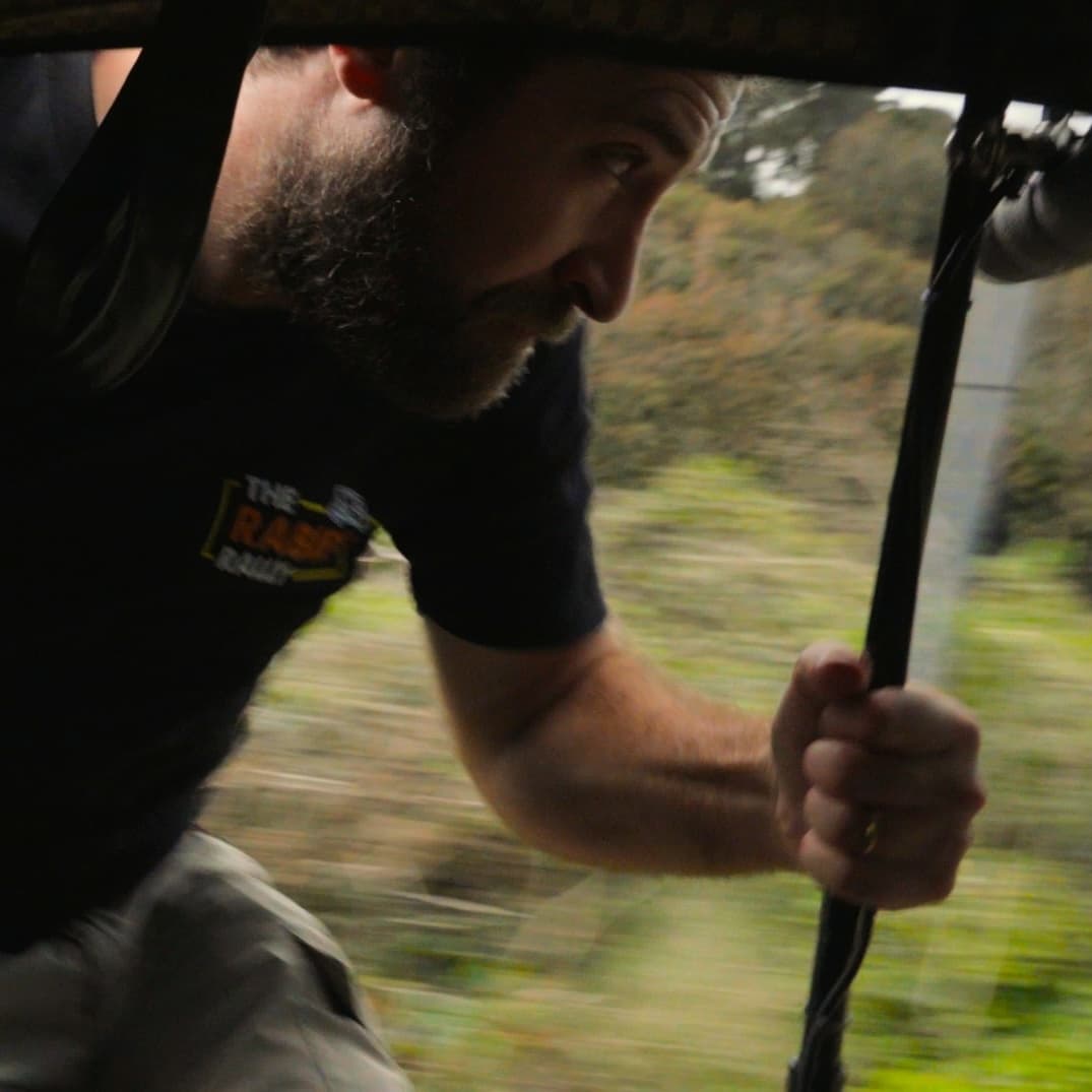 Fred holding on to the side of the tuk tuk